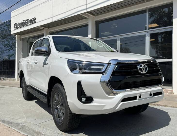 Toyota HILUX D/C 2.8 TDI AUTOMATICA SRV 4x4 0Km My2024 blanco perlado. Financia Bco. Santander. Acércate a ORIO HNOS, SAN GENARO, concesionario oficial JMC, ISUZU, KAMA Camiones